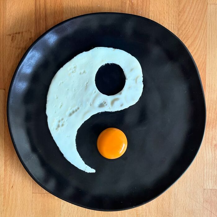 Creative egg art resembling a yin-yang symbol on a black plate.