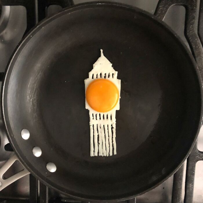 Creative egg art resembling a skyscraper in a frying pan with a sunny-side-up yolk.