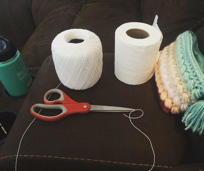 Scissors, string, toilet paper, and crochet set on a couch depicting funny pregnancy situations.