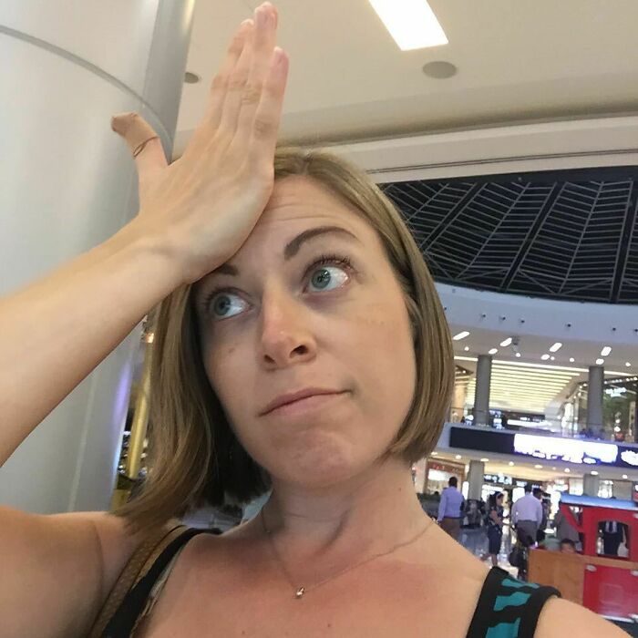 Woman in a shopping mall facepalming with a humorous expression, representing funny pregnancy situations.