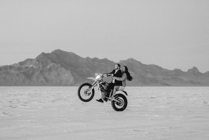 A couple on a motorcycle in a desert landscape, capturing a unique wedding photo moment.