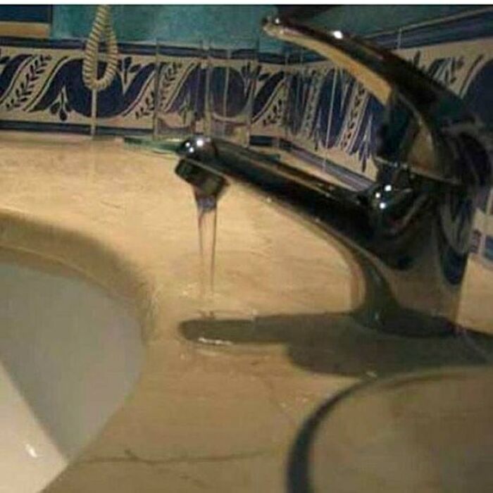 Construction mishap with faucet misaligned to the sink, water spills onto counter.