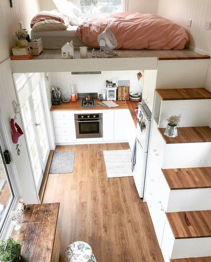Cozy interior of a tiny home featuring a lofted bed and modern kitchen, showcasing efficient small space living.
