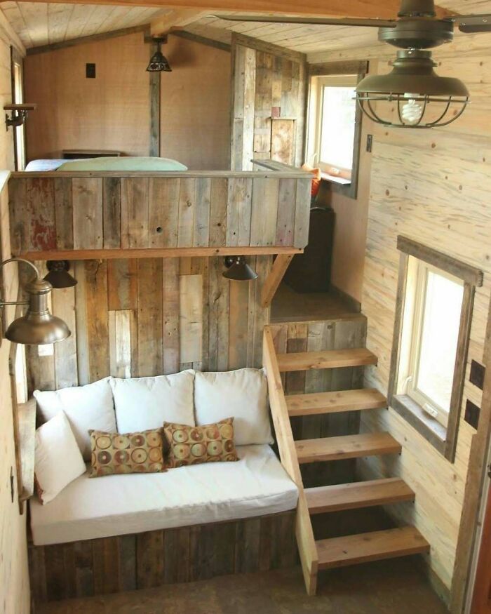 Cozy rustic tiny home interior with wooden loft and staircase.