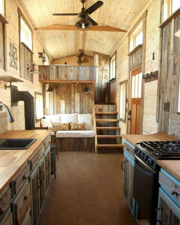 Rustic tiny home interior with wooden finishes, cozy loft, kitchen, and seating area.