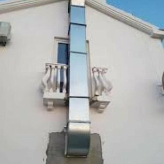 Construction fail: duct covering half a balcony on a white building.