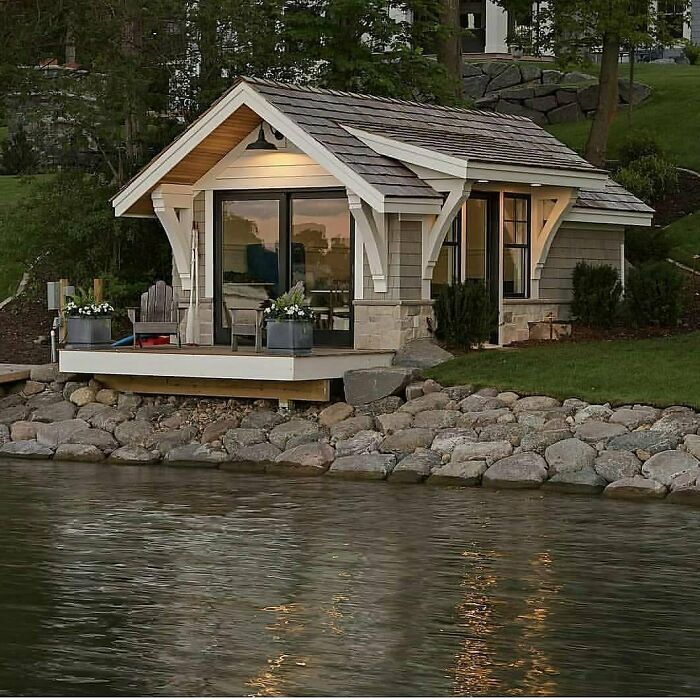 Charming tiny home by the water with large glass doors, wooden gable, and a cozy porch.