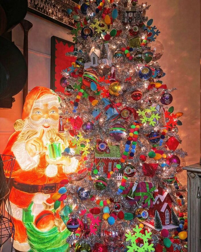 Colorful Christmas tree with diverse ornaments and a Santa Claus decoration.