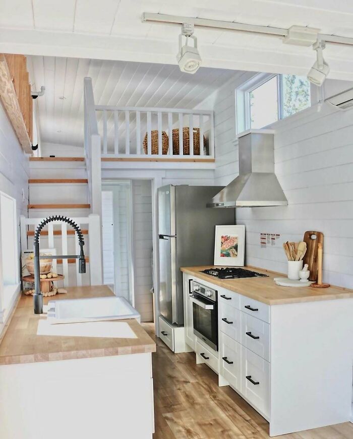 Bright interior of a tiny home kitchen with wooden countertops and modern appliances.