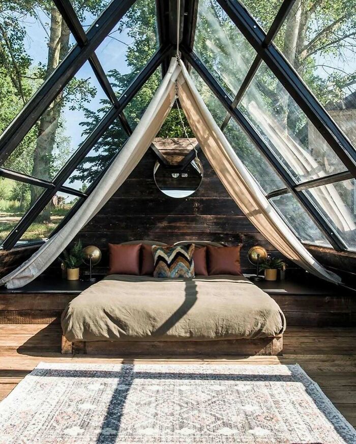 Stylish tiny home bedroom with large windows, cozy bed, and rustic decor.