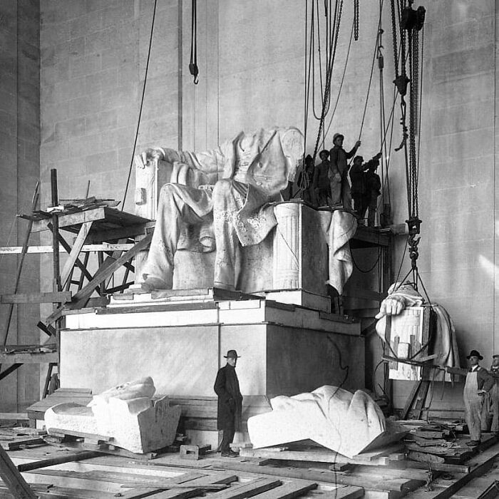 Historical construction of Lincoln Memorial statue, workers assembling large blocks, highlighting past architectural achievements.