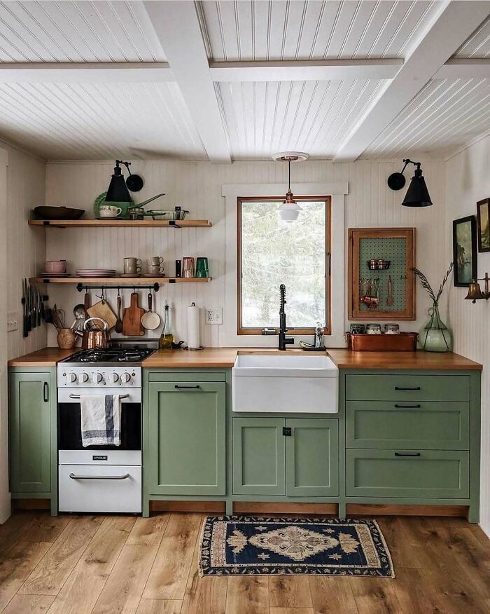 Cozy kitchen in a tiny home with green cabinets, farmhouse sink, and rustic decor.