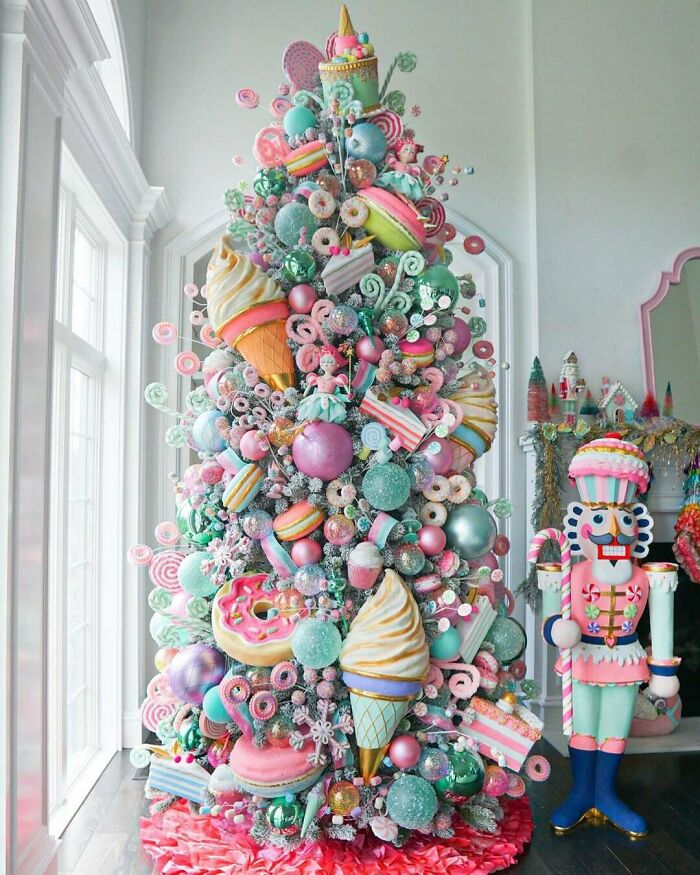 Whimsical Christmas tree decorated with candy-themed ornaments, featuring donuts and ice cream, next to a festive nutcracker.