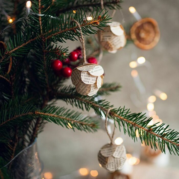 DIY Christmas decorations made from paper and berries on a tree branch.