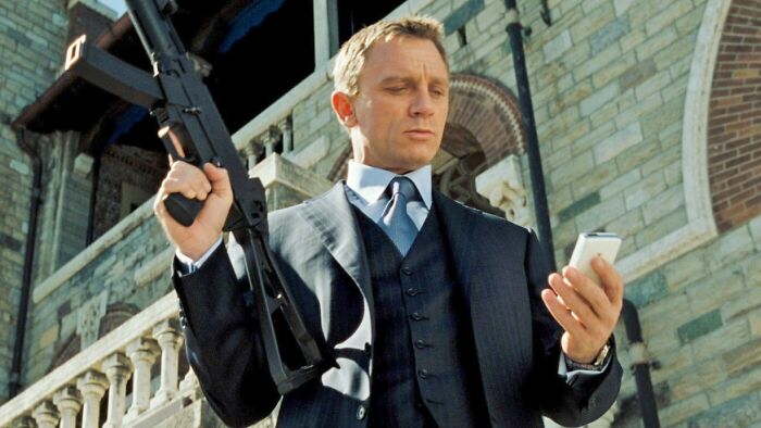 Man in a suit holding a rifle and phone, concept for fascinating fan theories in spy films.