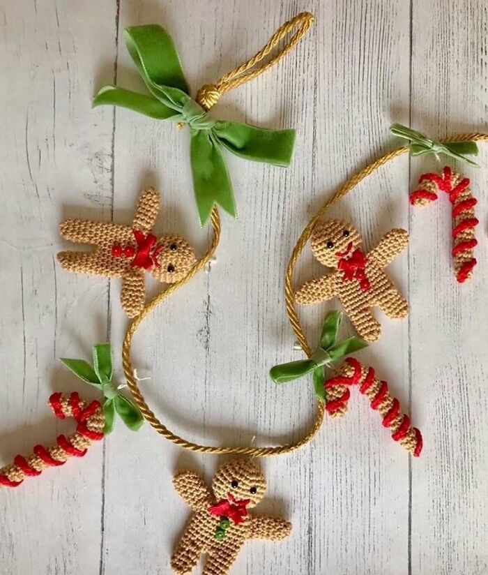 DIY Christmas decoration with knitted gingerbread men and candy canes on a rustic wood background.