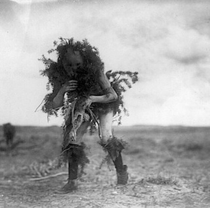 Individual dressed in camouflage, historical context, standing in open landscape.
