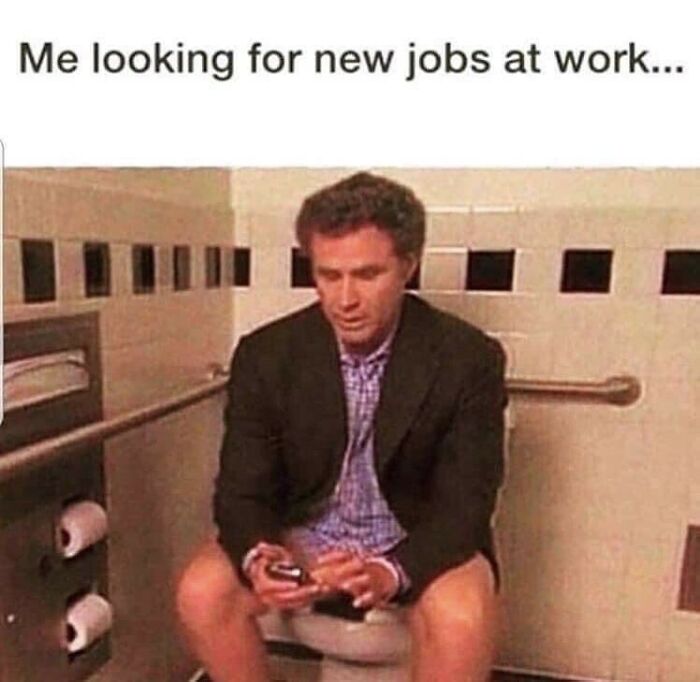 Man in a suit looking at his phone in a restroom, with text above about job searching; a humorous work meme.