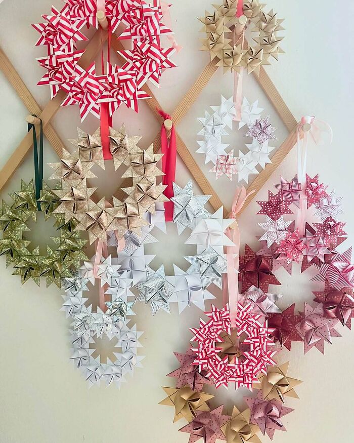 Creative DIY Christmas wreaths made of colorful paper stars, hanging on a wall with wooden accents and ribbons.
