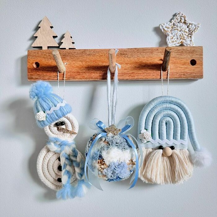 DIY Christmas decorations with a knitted snowman, ornament ball, and braided gnome hanging on a wooden rack.