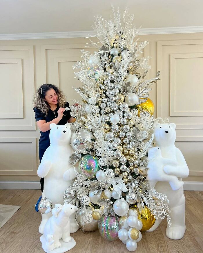 Woman decorating a white and gold Christmas tree with polar bear figures; a creative Christmas tree idea.