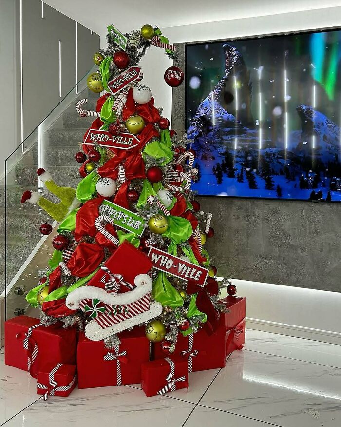 Whimsical Christmas tree decorated in Grinch and Who-ville theme, adorned with colorful ornaments and gift boxes.