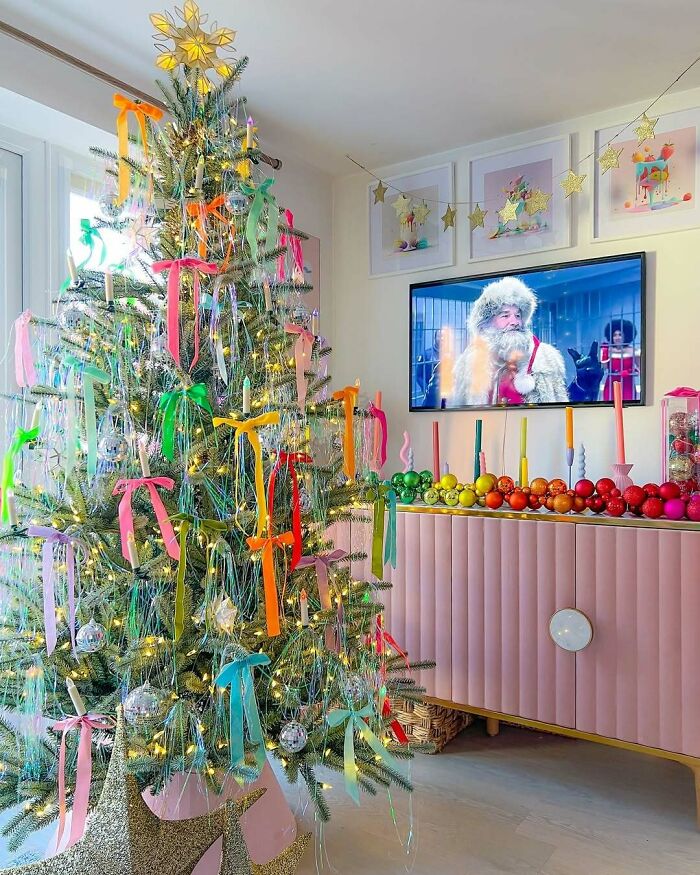 Colorful Christmas tree with ribbons and lights, festive room decoration.