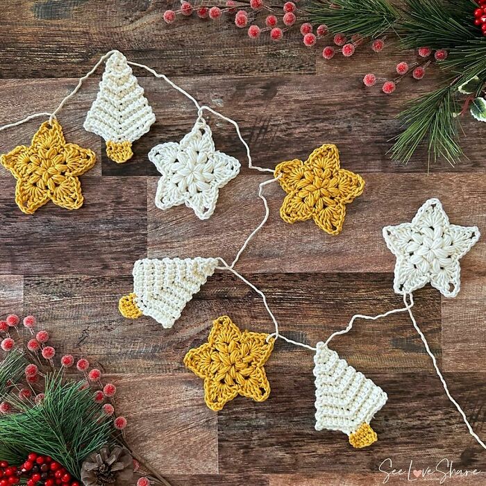 Crocheted DIY Christmas decorations featuring stars and trees on a string against a wooden background.