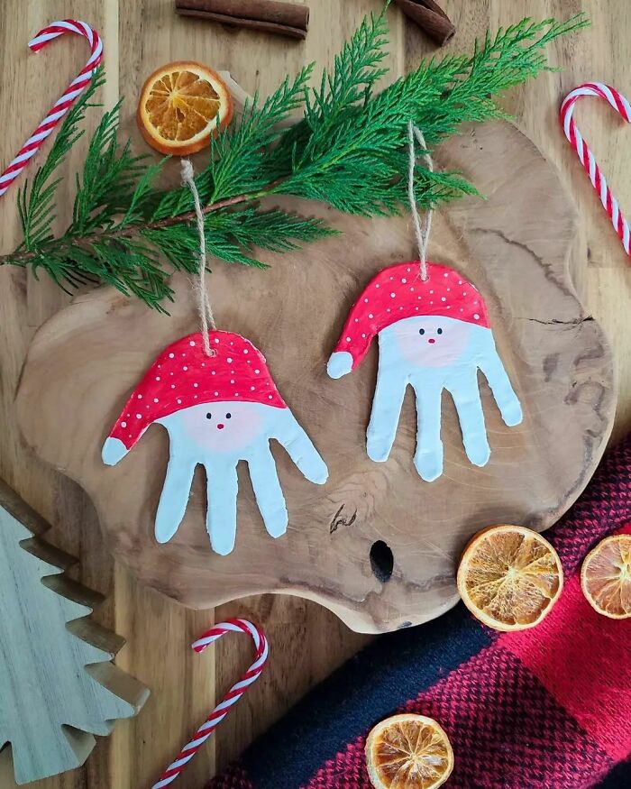 DIY Christmas decorations with handprint Santa crafts, candy canes, and dried orange slices on a wooden background.