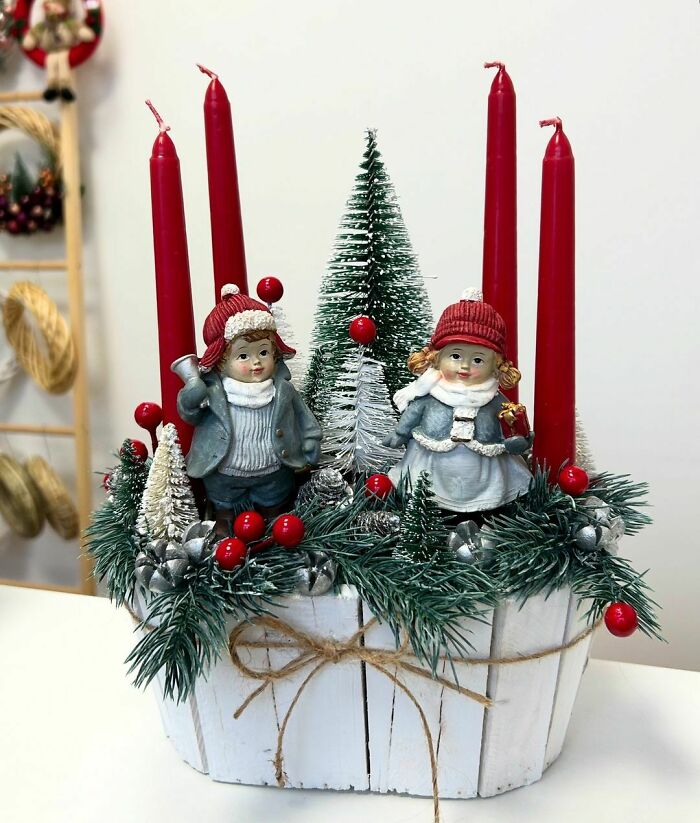 Festive Christmas decorating idea with candles, pine branches, and cute figurines in a rustic basket.