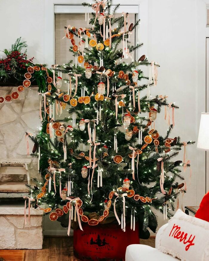 Christmas tree decorated with dried orange slices and ribbons in a cozy living room setting.