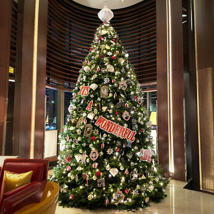 Luxuriously decorated Christmas tree in a modern lobby, featuring festive ornaments and a bright "It's a Wonderful Life" banner.