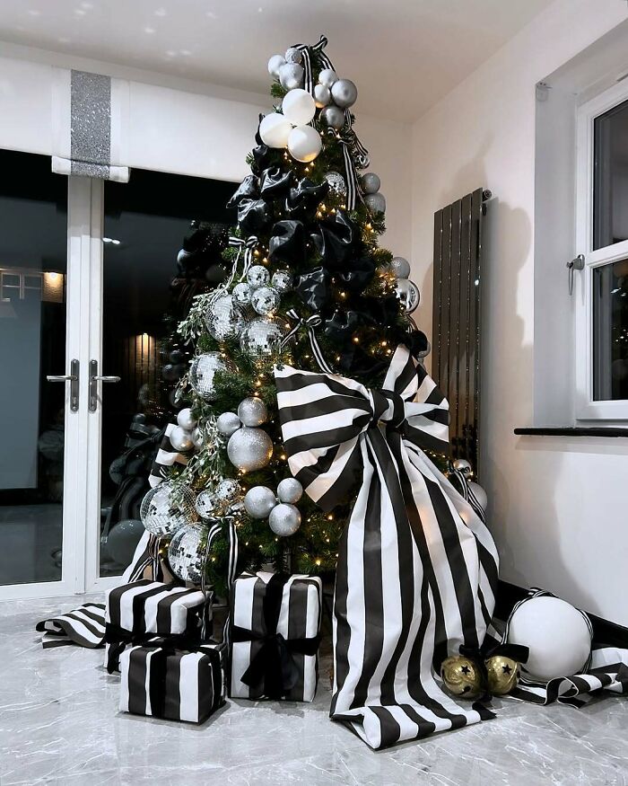 Black and white Christmas tree idea with striped ribbons, silver ornaments, and wrapped presents.