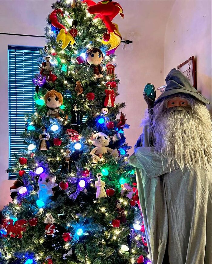 Magical-themed Christmas tree with colorful lights and ornaments, standing next to a wizard figure.