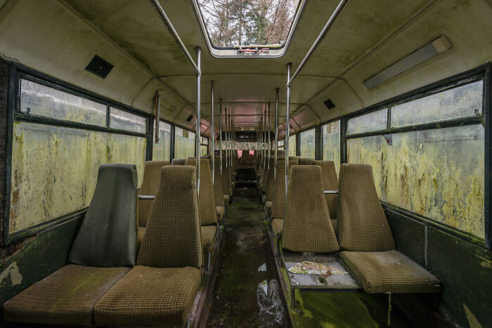 Interior of an abandoned Irish ghost bus with moss-covered seats and peeling paint.