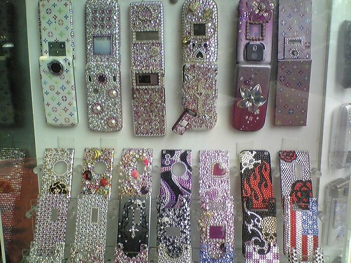 Collection of bejeweled old cell phone cases, showcasing nostalgic old-internet-feel designs with various patterns and embellishments.