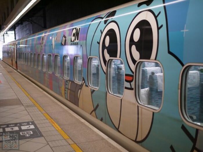 Train with cartoon character graffiti, evoking old internet feel, parked at a station.