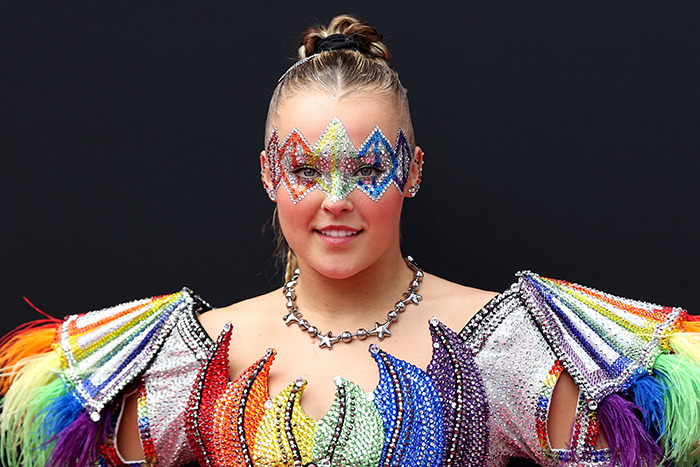 JoJo Siwa in a colorful costume at an event, related to the celebrity &ldquo;Ignore List&rdquo; trend.