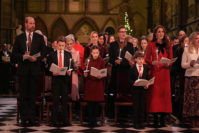 Royal family at Christmas service holding candles, children in red outfits. Royal family at Christmas service holding candles, children in red outfits.