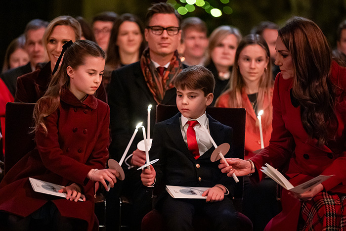 Princess Kate with her children, holding candles, dressed in festive attire. Princess Kate with her children, holding candles, dressed in festive attire.