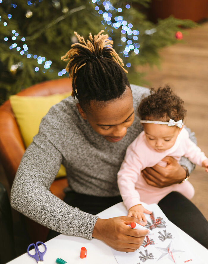 Father and daughter coloring together during Christmas, near a decorated tree. Father and daughter coloring together during Christmas, near a decorated tree.