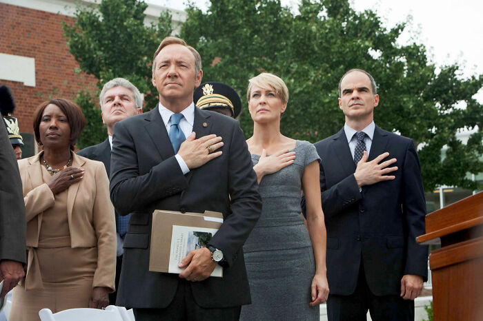 People standing outdoors with hands over hearts, possibly during a ceremony, related to fascinating fan theories.