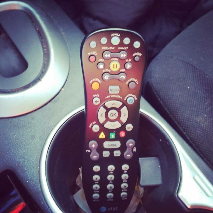 Remote control humorously placed in a car cup holder, illustrating funny pregnancy situations.