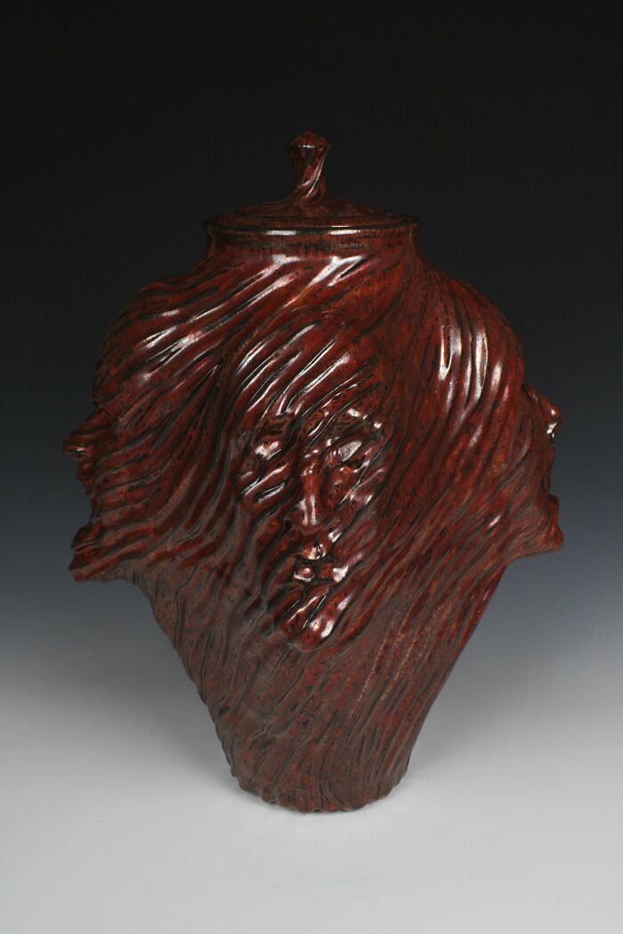 Surreal ceramic art featuring an intricate vase with multiple faces, showcasing emotional expression.