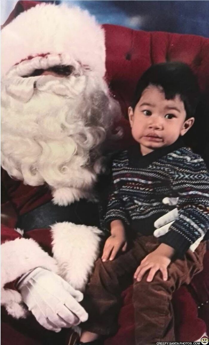 Child sitting next to a creepy Santa with a worried expression, Santa in red suit and white gloves.