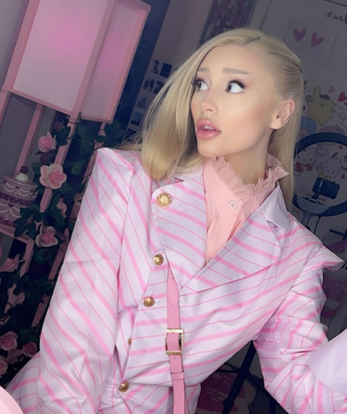Ariana Grande impersonator Paige Niemann in pink striped outfit poses in a flower-filled room, highlighting her significant weight loss. Ariana Grande impersonator Paige Niemann in pink striped outfit poses in a flower-filled room, highlighting her significant weight loss.