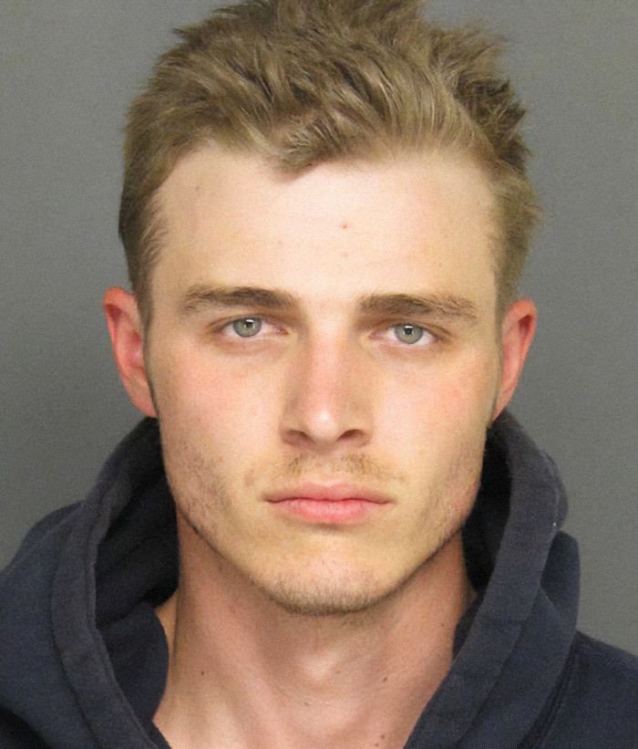 Jacob Miller in a mugshot, wearing a dark hooded sweatshirt. Viral criminal heartthrob image.