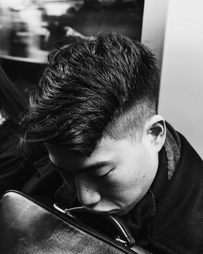 A man asleep on a Tokyo train, illustrating the toll of fast-paced life.