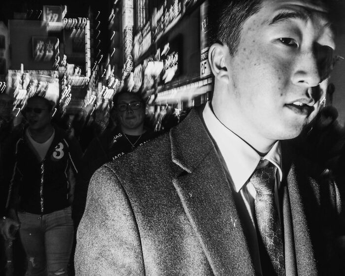 Black and white street photo capturing Tokyo's fast-paced life with people walking at night.