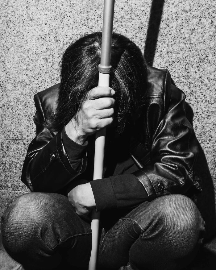 Black and white image of a person sitting against a wall, reflecting Tokyo's fast-paced life stress.